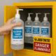 Hand placing alcohol hand sanitizer bottle into yellow fireproof Justrite cabinet for NFPA storage compliance.