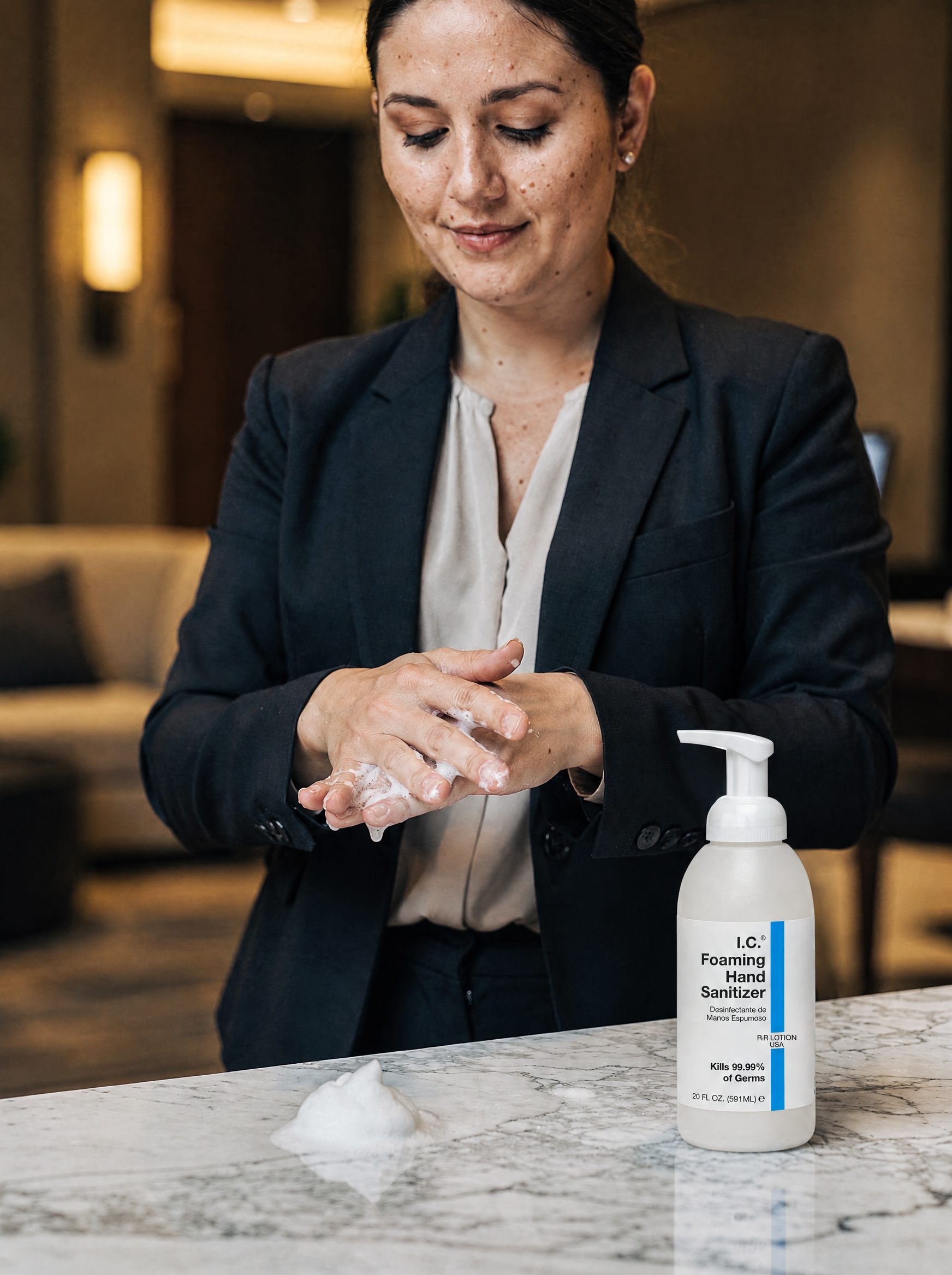 Hotel manager using I.C. Alcohol-Free Foaming Hand Sanitizer at a marble front desk