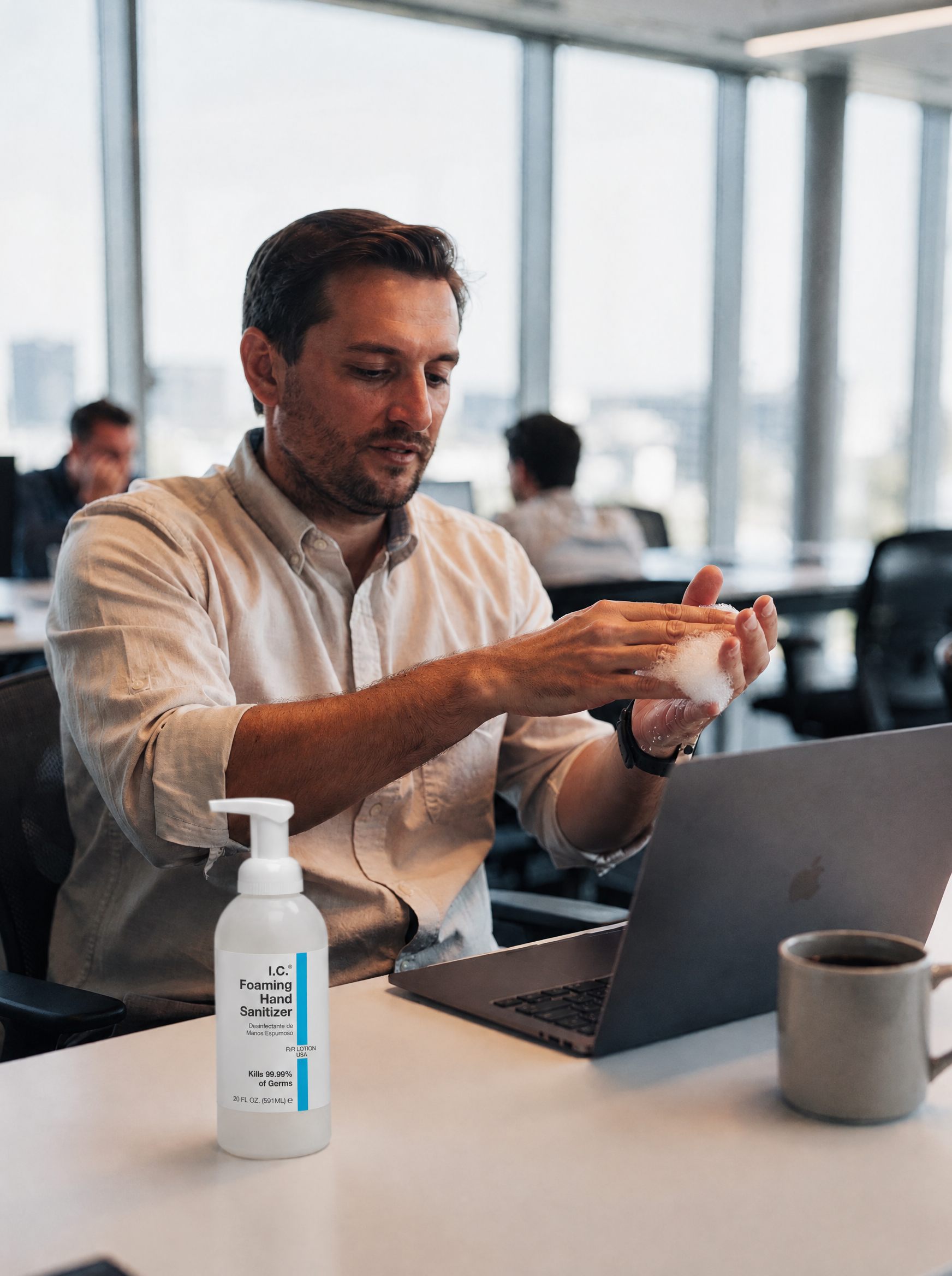 Office worker at his laptop with I.C. Alcohol-Free Foaming Hand Sanitizer on the desk